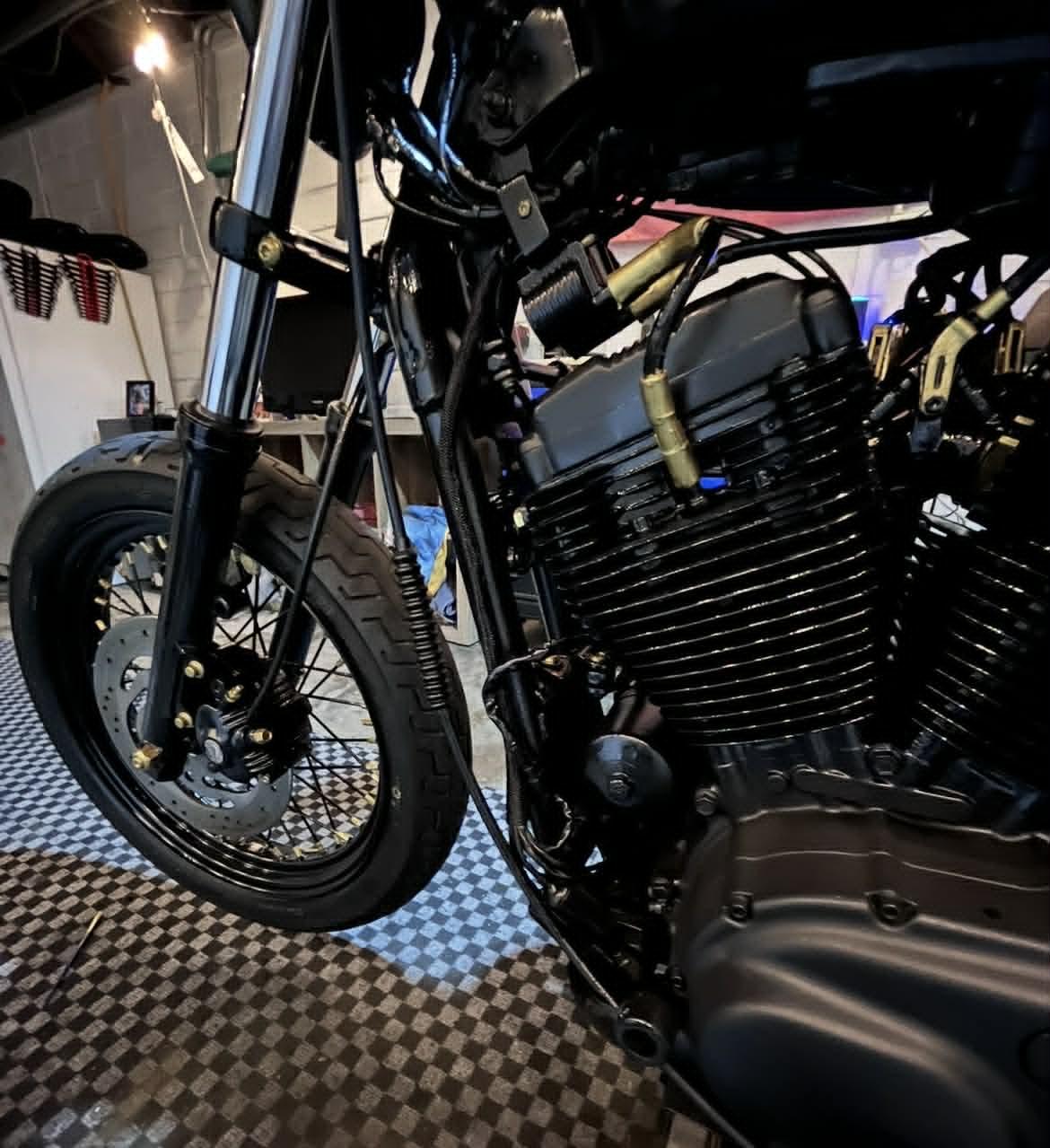 Freshly refinished V-twin on the bike — gloss black cases, gold accents, checkered shop floor