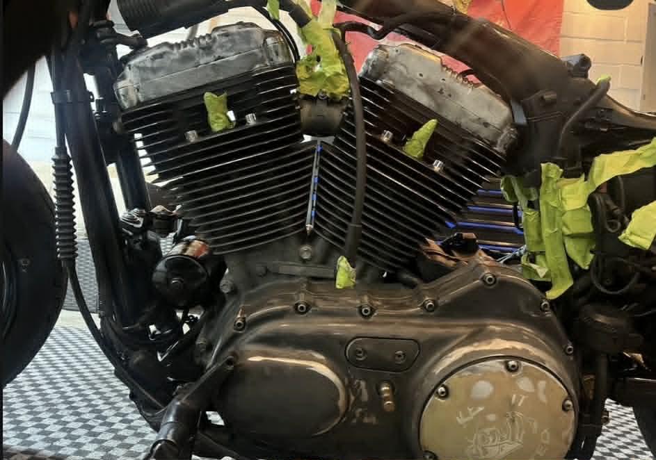 V-twin engine taped off pre-paint — dirty cylinders, raw heads
