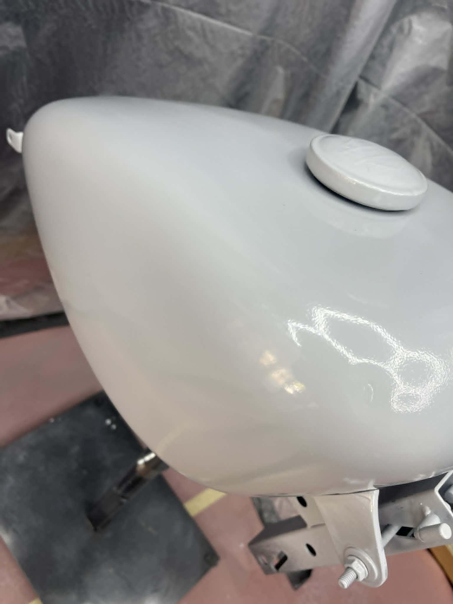 Sportster peanut tank in grey primer on a paint stand during prep